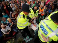 Police carry away a climate change activist blockading Waterloo Bridge on the third day of an environmental protest by the Extinction Rebellion group, in London on April 17, 2019. (Photo by Tolga AKMEN / AFP) (Photo credit should read TOLGA AKMEN/AFP/Getty Images)