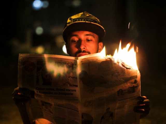 Man reading a burning newspaper