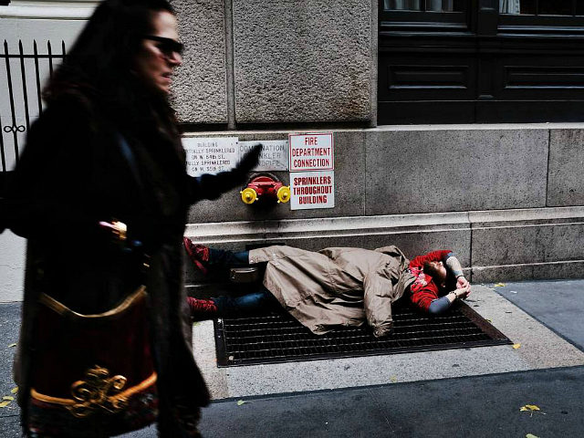 NEW YORK, NY - NOVEMBER 30: A woman walks by a homeless man along a Manhattan street on No