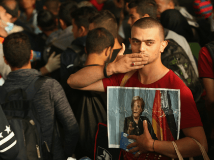 MUNICH, GERMANY - SEPTEMBER 05: A migrant from Syria holds a picture of German Chancellor