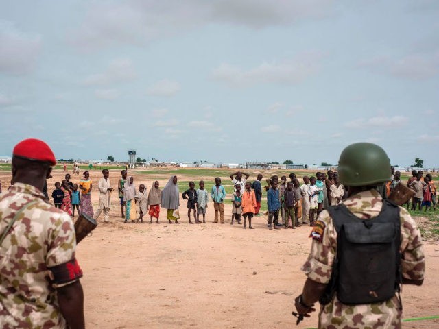 Soldiers patrol as children watch the medical outreach program at the Bakassi Internally Displaced Peoples (IDP) Camp on July 6, 2017 in Maiduguri. The Nigerian Military held the NADCEL 2017 free medical outreach project at Bakassi IDP Camp in Maiduguri. / AFP PHOTO / STEFAN HEUNIS (Photo credit should read …
