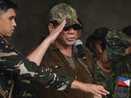 TOPSHOT - Philippines' President Rodrigo Duterte (C) salutes in front of soldiers after de