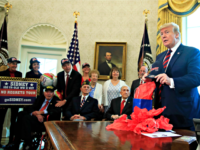 President Donald Trump is presented with a cap by World War II veterans, seated from left, Sidney Walton, joined by fellow WW II veterans Allen Jones, Paul Kriner and Floyd Wigfield, in the Oval Office of the White House in Washington, Thursday, April 11, 2019. (AP Photo/Manuel Balce Ceneta)