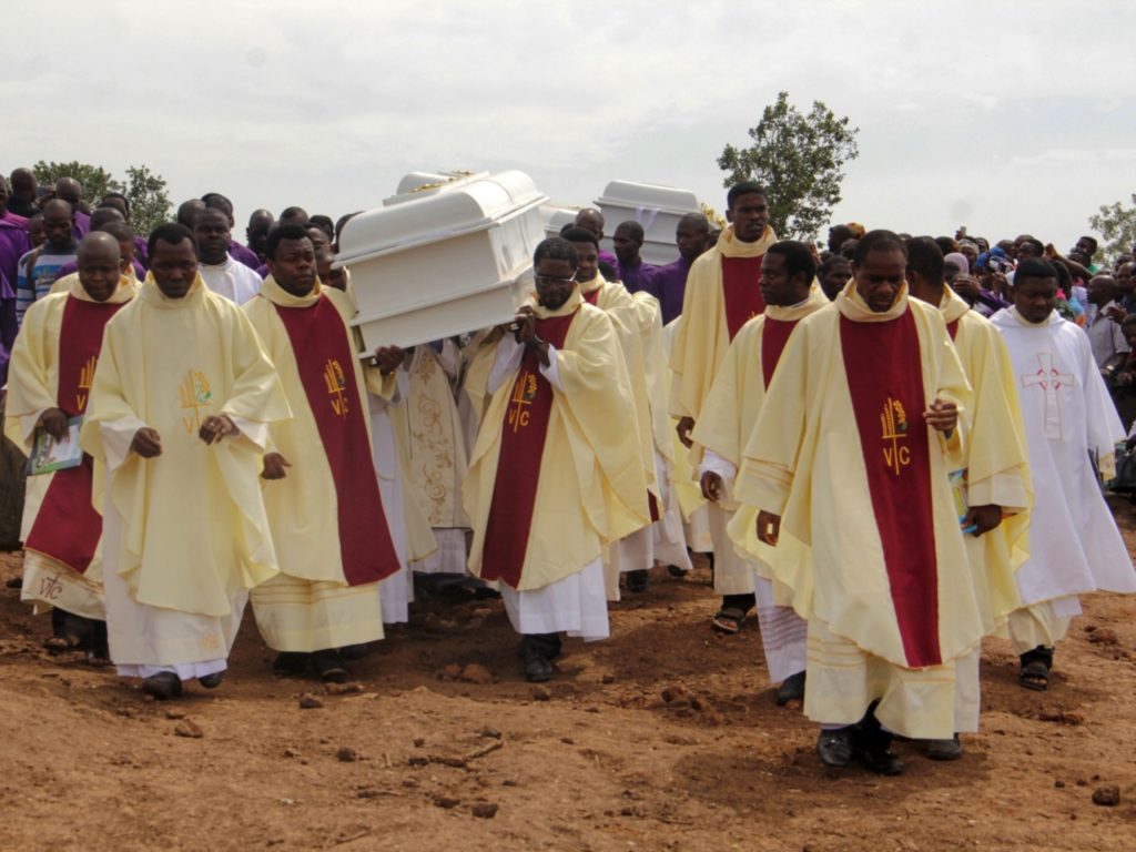 Clergymen carry white coffins containing bodies of priests allegedly killed by Fulani herdsmen for burial at Ayati-Ikpayongo in Gwer East District of Benue State, north-central Nigeria, May 22, 2018. - Two Nigerian priests and 17 worshipers have been buried , nearly a month after their church was attacked, as Catholics took to the streets to demand an end to a spiral of violence.  White coffins containing the bodies of clerics and members of their congregation have been laid in central Benue state, which has been hit by a wave of deadly unrest.  (Photo by EMMY IBU / AFP) (Photo credit should be EMMY IBU/AFP/Getty Images)