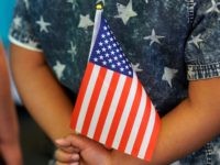 SALT LAKE CITY, UT - APRIL 10: A school child holds an American Flag behind his back at a Naturalization Ceremony on April 10, 2019 in Salt Lake City, Utah. There were 49 people from 26 countries that became U.S. citizens. A group of Republican Senators are introducing a bill …