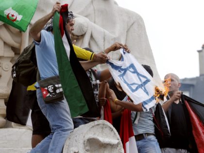 Pro-Palestinian demonstrators burn an Israeli national flag after climbing on the Republic monument, on the Republique square in Paris, during a banned demonstration against Israel's military operation in Gaza and in support of the Palestinian people, on July 26, 2014. French authorities banned on July 26, 2014 a new pro-Palestinian …