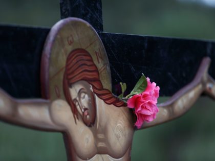 A rose is placed on a crucifix ahead of a Good Friday reenactment of Christ being taken do