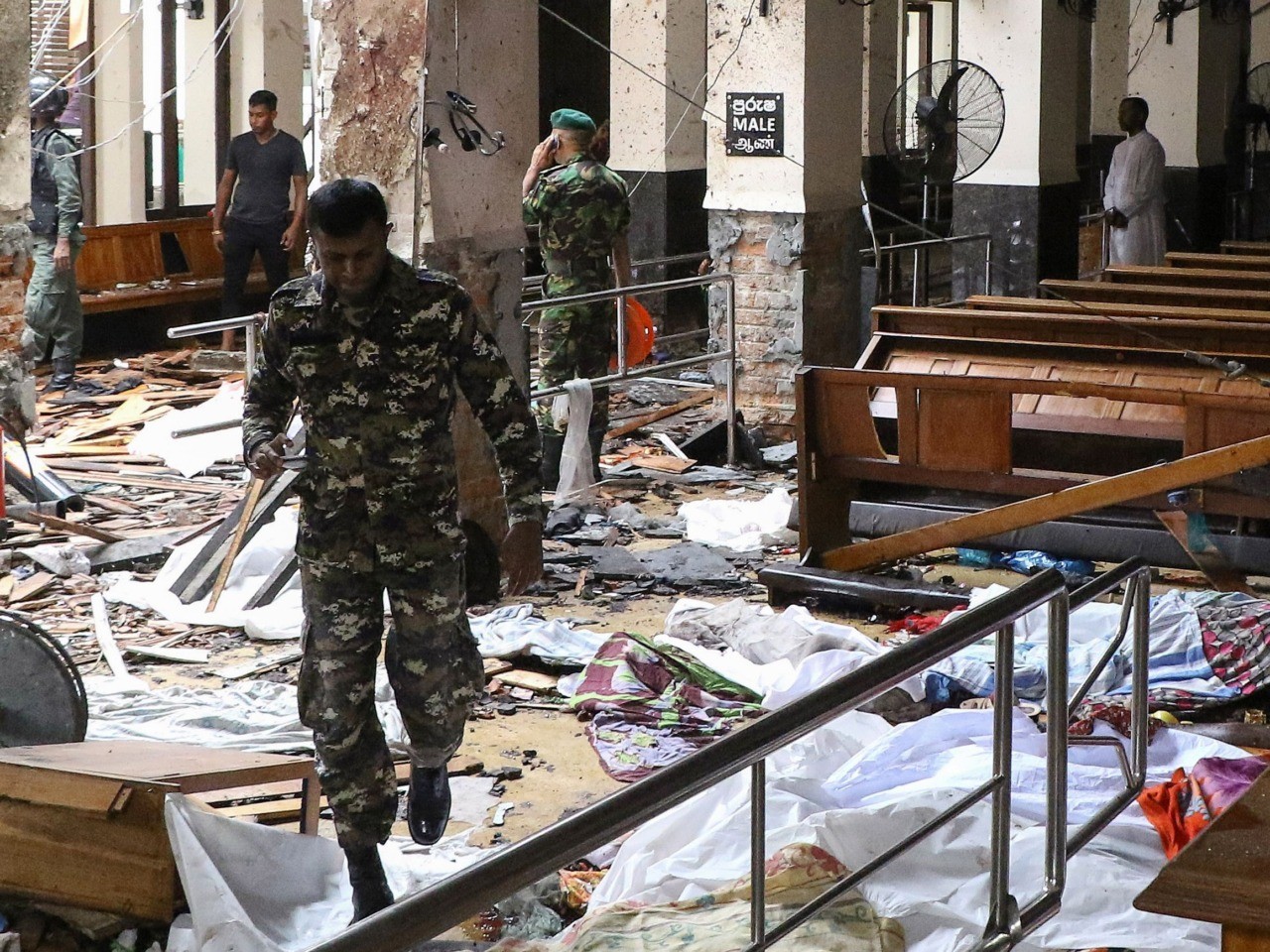 Graphic content / Sri Lankan security personnel walk past dead bodies covered with blankets amid blast debris at St. Anthony's Shrine following an explosion in the church in Kochchikade in Colombo on April 21, 2019. - A string of blasts ripped through high-end hotels and churches holding Easter services in Sri Lanka on April 21, killing at least 156 people, including 35 foreigners. (Photo by ISHARA S. KODIKARA / AFP) (Photo credit should read ISHARA S. KODIKARA/AFP/Getty Images)