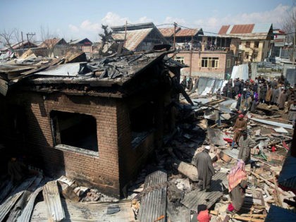 Kashmiri villagers inspect a damaged house after a gun battle in Hajin village, north of S