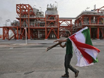 In this Saturday, March 16, 2019 photo, an Iranian worker carries Iranian flags prior to a