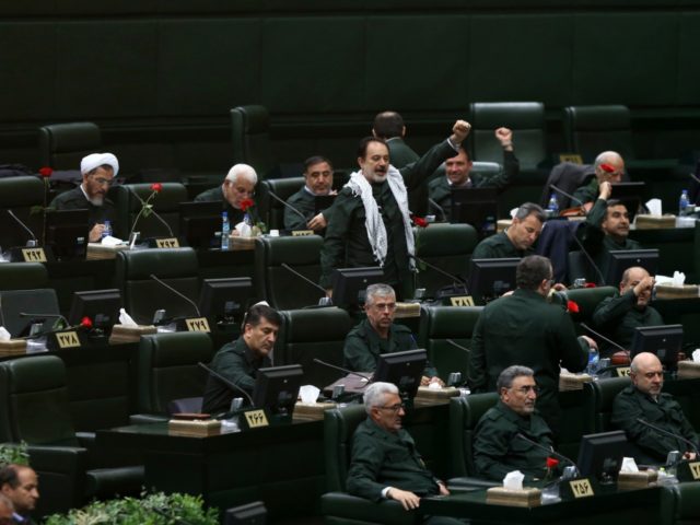 Wearing the uniform of the Iranian Revolutionary Guard, lawmakers chant slogan during an o