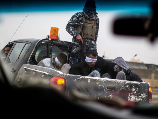 TOPSHOT - Christian militia fighters from the Nineveh Plain Protection Units (NPU) drive a pick-up truck in Qaraqosh (also known as Hamdaniya), transporting four men, allegedly members of the Islamic State (IS) group that were found inside a tunnel in Mosul, on December 20, 2016. / AFP / JM Lopez …