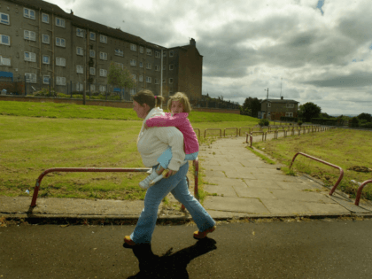 GLASGOW, SCOTLAND - JUNE 16: A young mother carries her child from school in the Barlanark area June 16, 2004 of Glasgow, Scotland. The Barlanark area has been identified in a survey as officially being the most deprived area of Scotland. The study measures deprivation by health, housing, income, unemployment …