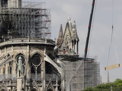 A crane lifts up construction material as scaffoldings surround Notre-Dame Cathedral in Pa