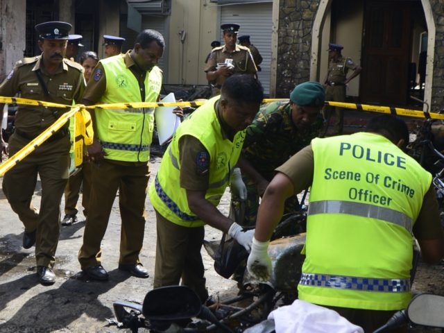 Sri Lankan security personnel and police investigators look through debris outside Zion Ch