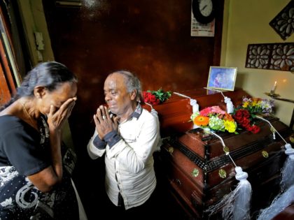 Baby Joseph Gomes prays standing next to coffins of his family members killed in the Easte