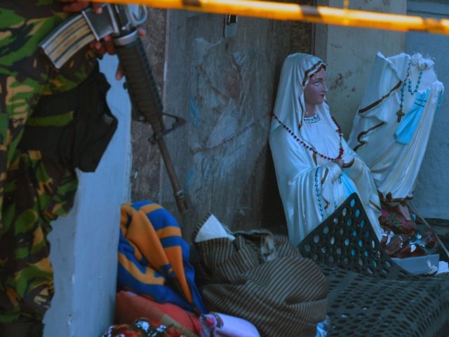 A member of the Sri Lankan security forces stands next to a broken Virgin Mary statue at S