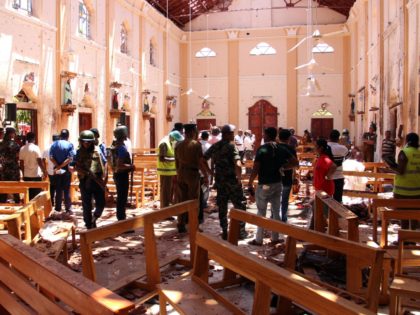 Sri Lankan security personnel walk through debris following an explosion in St Sebastian's