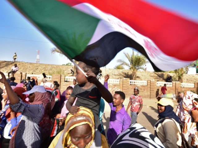 A young Sudanese boy waves a national flag as people celebrate after an announcement made by Sudan's new military ruler, in the Sudanese capital Khartoum, on April 13, 2019. - General Abdel Fattah al-Burhan vowed today to 'uproot' deposed president Omar al-Bashir's regime and release protesters, in a bid to …