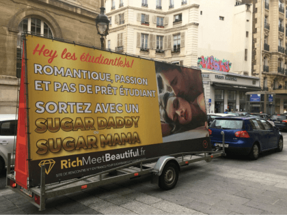 An advertising board of the dating site 'RichMeetBeautiful' reading 'students, &hell