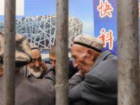 Ethnic Uighur men talk under an Olympic poster in Xinjiang's famed Silk Road city of Kashgar in China's far northwestern, mainly Muslim Xinjiang region on August 6, 2008. Gauging Olympic fervour in this tense city depends on whether you ask a member of the Muslim Uighur ethnic group or a …