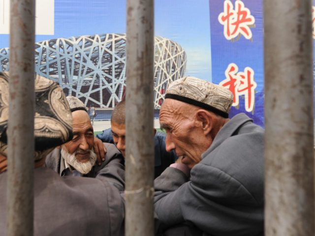 Ethnic Uighur men talk under an Olympic poster in Xinjiang's famed Silk Road city of Kashg