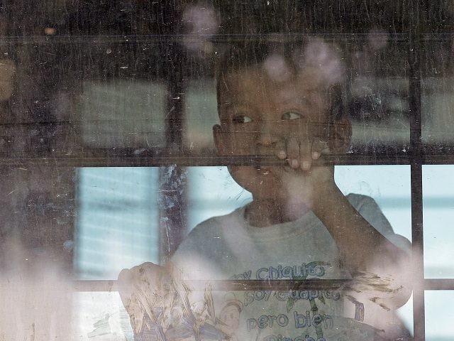 An immigrant child looks out from a U.S. Border Patrol bus leaving as protesters block the street outside the U.S. Border Patrol Central Processing Center Saturday, June 23, 2018, in McAllen, Texas. Additional law enforcement officials were called in to help control the crowd and allow the bus to move. …