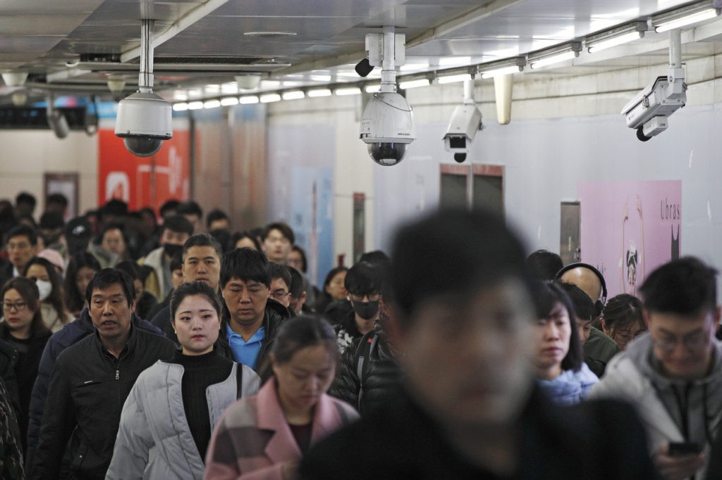 Commuters walk by surveillance cameras installed at a walkway in between two subway stations in Beijing, Tuesday, Feb. 26, 2019. Chinese government has using the facial recognition to monitor people for it "social credit" system. Millions of people in China has blocked from buying plane tickets last year under a controversial "social credit" system which part of efforts by President Xi Jinping's government to use data-processing and other technology to tighten control over society. (AP Photo/Andy Wong)