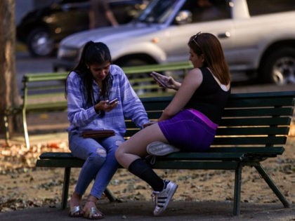 Locals check their mobile phones in a WiFi connectivity area, during a power outage in Caracas on March 9, 2019. - Venezuela President Nicolas Maduro claimed that a new cyber attack had prevented authorities from restoring power throughout the country following a blackout on March 7 that caused chaos. The …