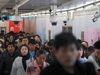Commuters walk by surveillance cameras installed at a walkway in between two subway stations in Beijing, Tuesday, Feb. 26, 2019. Chinese government has using the facial recognition to monitor people for it "social credit" system. Millions of people in China has blocked from buying plane tickets last year under a …