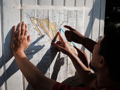 SANTIAGO NILTEPEC, MEXICO - OCTOBER 29: Some of the thousands of Central American migrants look at a map after arriving into the small town of Santiago Niltepec on October 29, 2018 in Santiago Niltepec, Mexico. Following a break on Sunday, the migrants, many of them fleeing violence in their home …