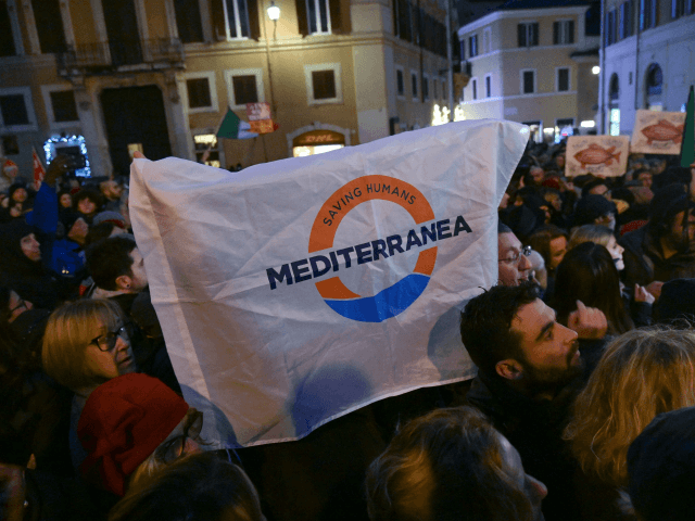 Demontrators hold a flag reading "Savin Humans - Mediterranea" during a gathering organized by local human rights associations in support of the 47 migrants including minors, stranded aboard the Dutch-flagged rescue vessel Sea Watch 3, in front of Italian parliament, in central Rome on January 28, 2019. - Save the …