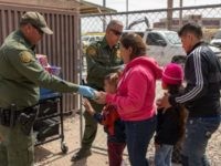 Border Patrol agents providing food and drinks to migrants in an El Paso migrant family processing center. (Photo by Mani Albrecht/U.S. Customs and Border Protection via Getty Images)