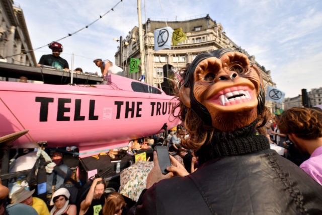 LONDON, ENGLAND - APRIL 18: A Climate protester wearing a monkey mask gathers around a boat at Oxford Circus during the fourth day of a coordinated protest by the Extinction Rebellion group on April 18, 2019 in London, England. More than 100 arrests have been made, with demonstrations blocking a …
