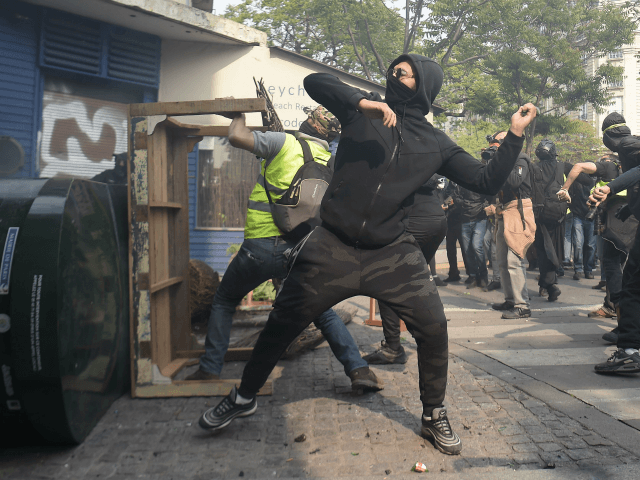 Protesters throw projectiles from behind a baricade during clashes with police on the sidelines of a May Day demonstration in Paris, on May 1, 2019. - Paris riot police fired teargas as they squared off against hardline demonstrators among tens of thousands of May Day protesters, who flooded the city …