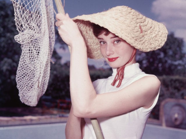 Portrait of Belgian-born American actress Audrey Hepburn (1929 - 1993) as she wears a peculiar hat and sleeveless blouse and holds a pool cleaning net beside a dry swimming pool, early 1950s. (Photo by Hulton Archive/Getty Images)