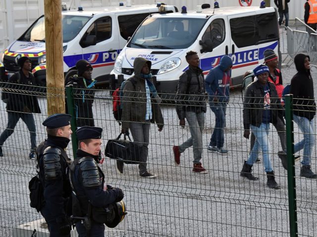 Police officer stand guard as unaccompanied migrant minors, from the demolished "Jung