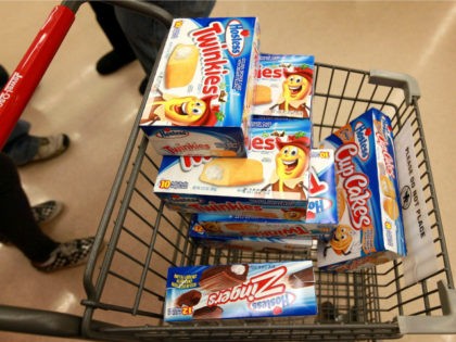 A customer heads to the checkout with a shopping cart loaded with Hostess snacks at a Jewe