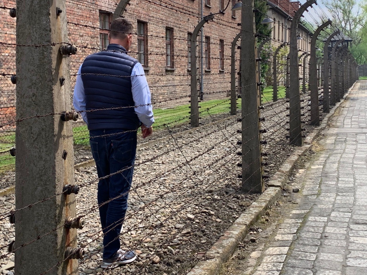 U.S. Ambassador to Germany Richard Grenell examines the barbed wire enclosure at Auschwitz.
