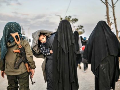 Veiled women reportedly associated with ISIS walk under the supervision of a female fighte