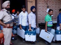An Indian Punjab Police personnel stands guard as election officials carry Electronic Voting Machines (EVM) and Voter-Verified Paper Audit Trail (VVPAT) leaving a distribution centre in Amritsar on May 18, 2019, on the eve of the 7th and final phase of India's general election. (Photo by NARINDER NANU / AFP) …