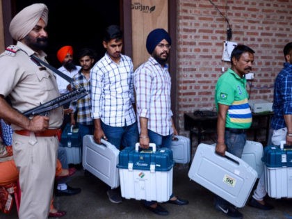 An Indian Punjab Police personnel stands guard as election officials carry Electronic Voti