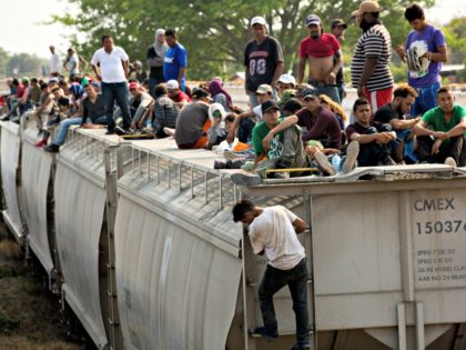 Central American migrants wait on the top of a parked train during their journey toward th