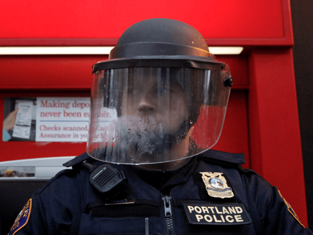 A policeman in riot gear defends a Bank of America as protesters march past various banks November 17, 2011 in Portland, Oregon. The Occupy Portland movement joined the nationwide N17 protests today, targeting downtown banks. (Photo by Natalie Behring/Getty Images)