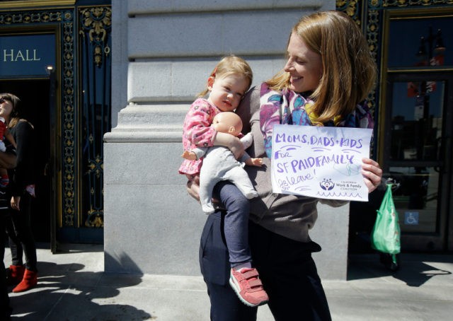 A mother shows support for paid parent leave at a 2016 San Francisco rally. The city was the first in the nation to require full pay for six weeks of baby bonding leave. Fifty-five percent is covered by employee disability paycheck deductions, and the rest by employers.(AP Photo/Jeff Chiu)