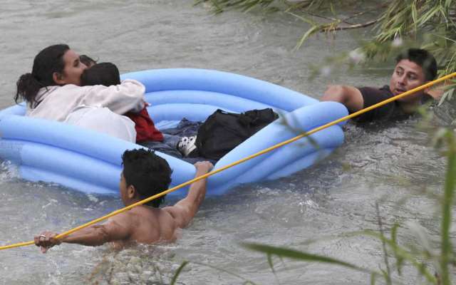 A migrant Honduran family struggles to reach the U.S. bank of the Rio Grande in a makeshift raft. (Photo Bob Owen/San Antonio Express-News via AP)