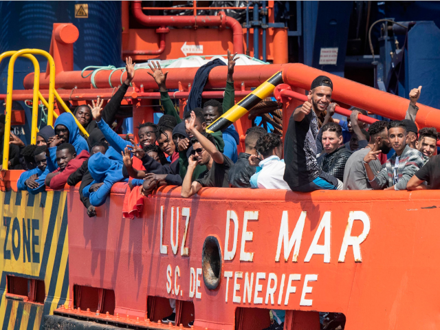 Migrants wave aboard a Salvamento Maritimo sea search and rescue agency vessel after they were rescued from a boat stranded in the Strait of Gibraltar during a rescue operation with the Spanish Guardia Civil on September 8, 2018.