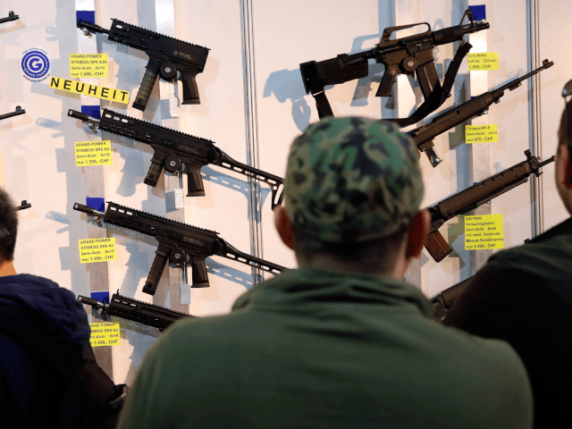 Visitors look at semi-automatic shotguns displayed on a wall during the 45th edition of the Arms Trade Fair, in Lucerne, on March 29, 2019. - Switzerland, where gun culture has deep roots, has managed to avoid the charged national debates surrounding firearm ownership that have consumed other countries. But in …