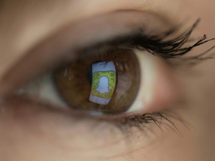 An illustration picture taken on March 22, 2018 in Paris shows a close-up of the Snapchat logo in the eye of an AFP staff member posing while she looks at a flipped logo of Snapchat. / AFP PHOTO / Christophe SIMON (Photo credit should read CHRISTOPHE SIMON/AFP/Getty Images)