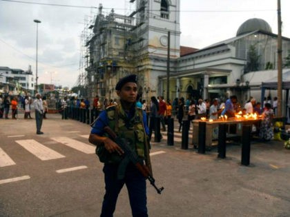 A Sri Lankan Navy personnel stands guard as Catholic devotees pray at St Anthony's church